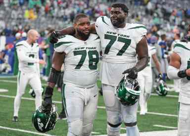 New York Jets guard Laken Tomlinson (78) and offensive tackle Mekhi Becton (77) walk off the field after defeating the New York Giants in overtime at MetLife Stadium.