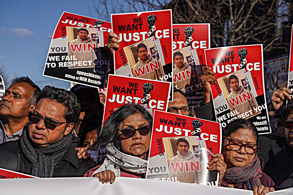 Protesters hold up signs with Win Rozario's image