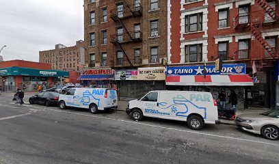 Daytime view of a street in the Bronx with white trucks parked in front