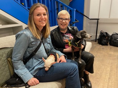 two women, each holding a small dog at a benefit for dog rescues in SoHo, NYC