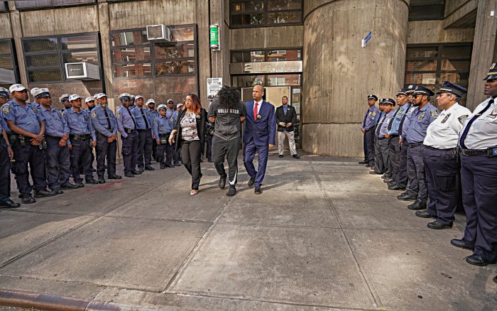 Traffic agents look on as perp walked out of Harlem precinct