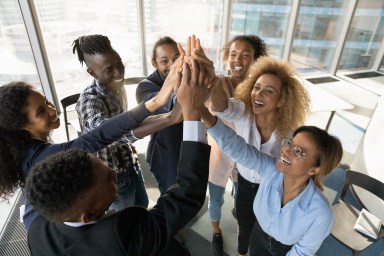 Friendly young african colleagues joining hands in air.