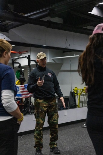 man teachers two women self defense in a gym