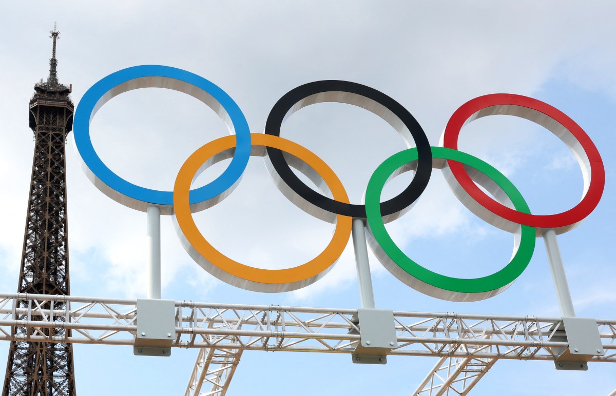 The five olympic rings displayed in front of the top of the eiffel tower