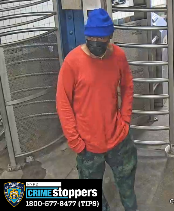 man in Brooklyn train station wearing blue hat and orange shirt