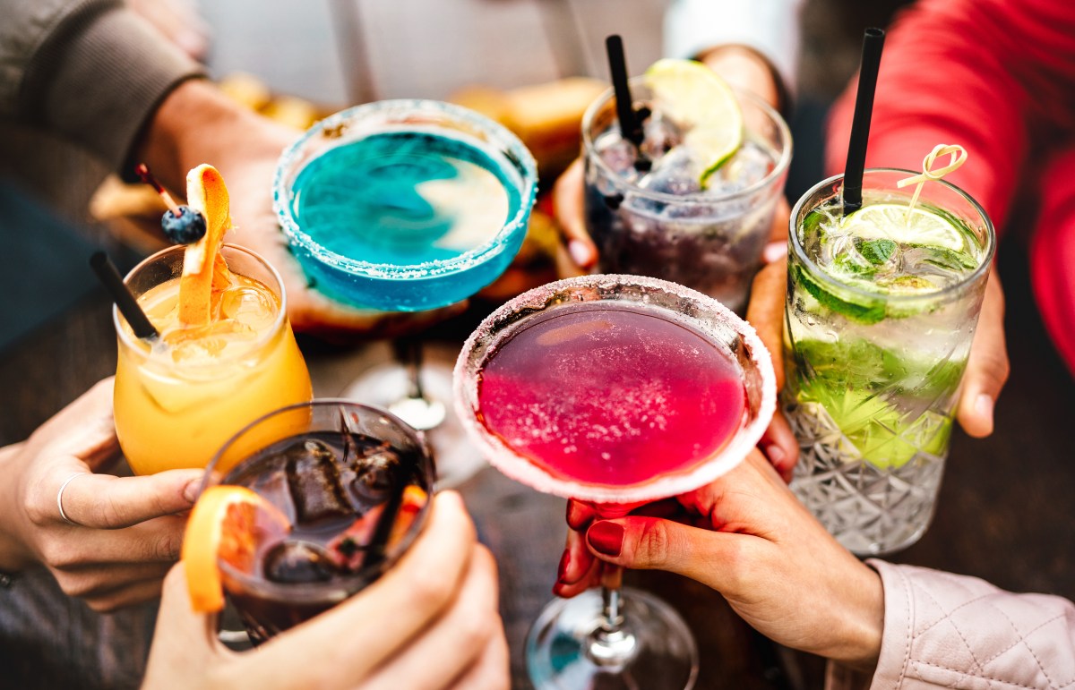 People hands toasting multicolored fancy drinks – Young friends having fun together drinking cocktails at happy hour – Social gathering party time concept on warm vivid filter