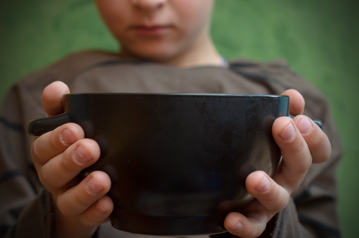 The palms of the hungry boy hold an empty plate.