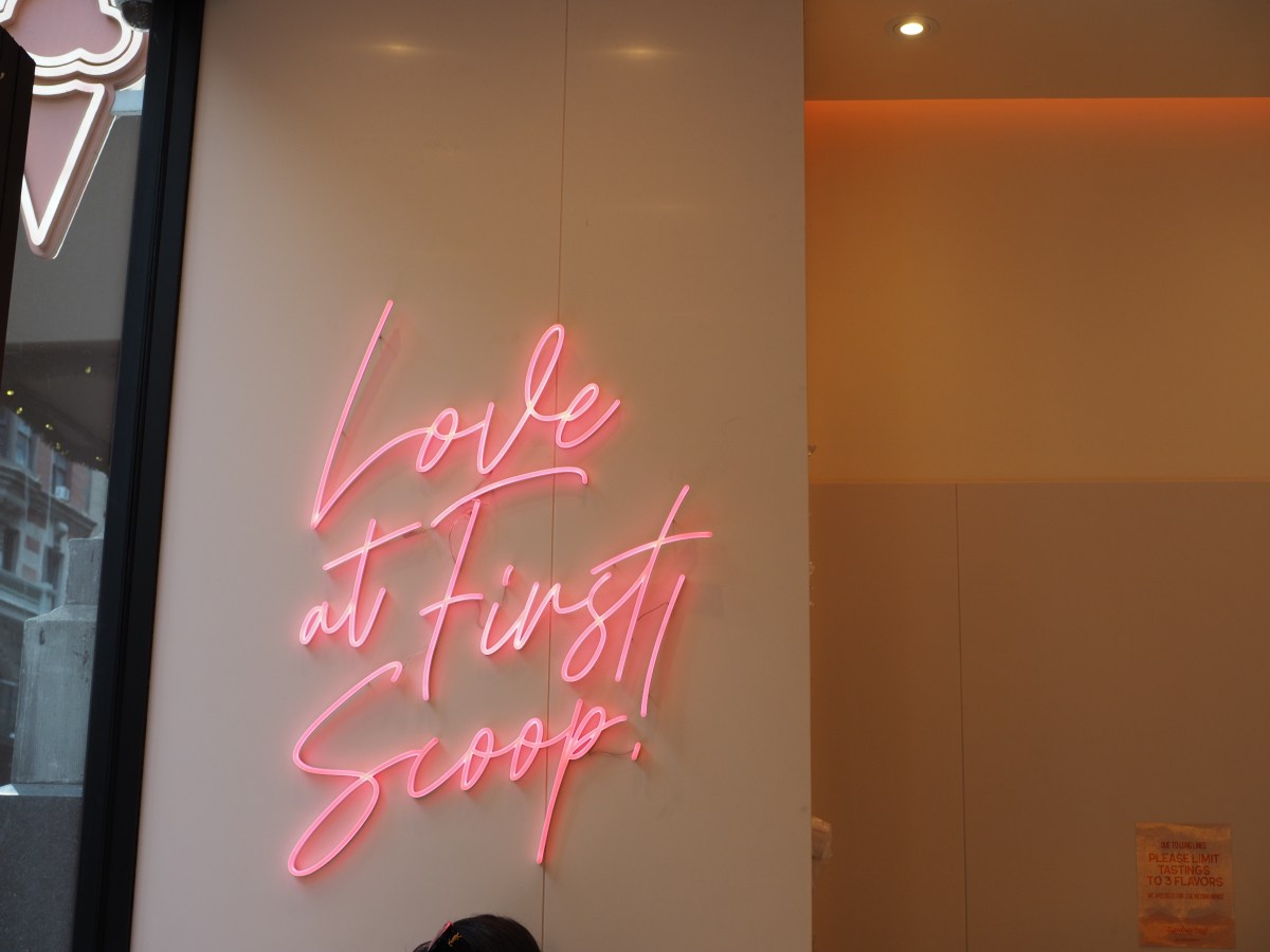 a pink neon sign on the wall reads love at first scoop.