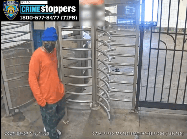 man in Brooklyn subway station wearing blue hat and orange shirt