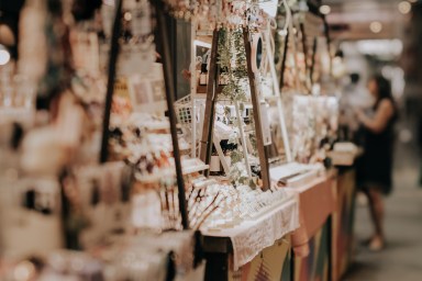 Indoor festive weekend market. Social pop up event of entrepreneurs and makers selling their goods at their booths in shopping mall. Captured with a tilt-shift lens. Selective focus; bokeh effect.