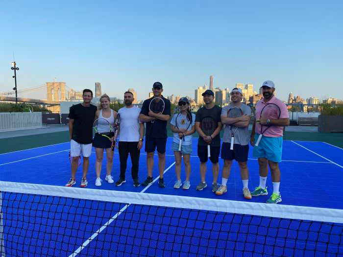 several people, at least most being US Open fans, with Andy Roddick on a tennis court at the Seaport in Lower Manhattan