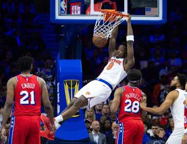 New York Knicks forward OG Anunoby (8) dunks the ball in front of Philadelphia 76ers center Joel Embiid (21) and forward Guerschon Yabusele (28) during the fourth quarter at Wells Fargo Center.