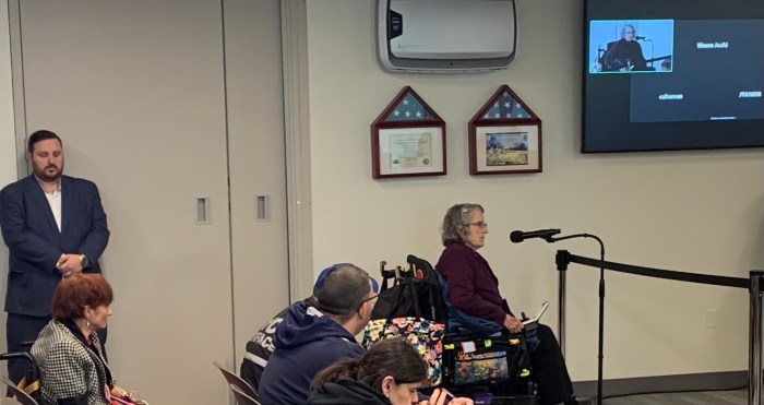 woman at a podium speaking about more accessible subway stations in NYC 