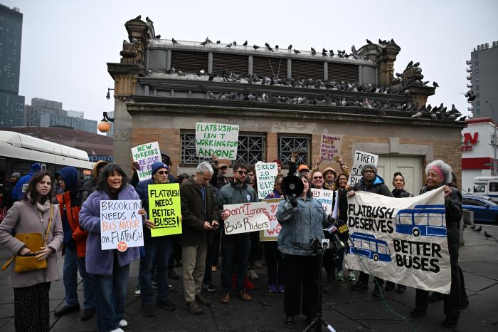 These 24 MTA local and express buses slated for increased service next year 2 people outside near a bus stop rallying for better bus service in Brooklyn