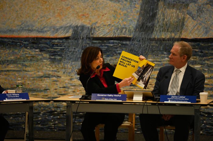 Congestion pricing: Hochul dismisses Trump admin's demand for deadline to end Manhattan toll program 2 a woman holds up a book at a table showing info about congetion pricing