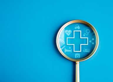 Healthcare service, hospital website online search, wellness plan and insurance concept. Health, care and medical element icon symbols in magnifying glass lens on blue background with copy space.