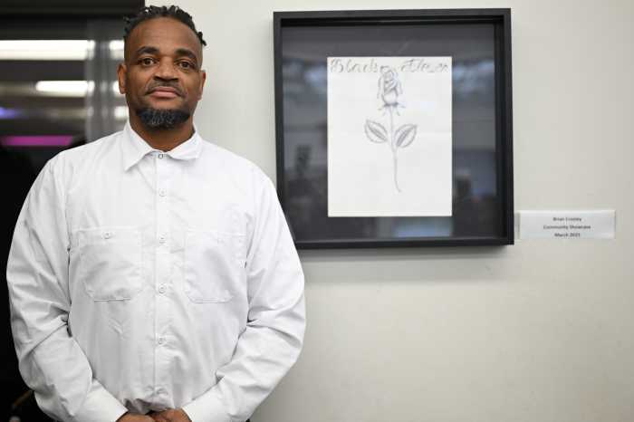 Brian Croskey poses alongside his artwork 'Black Flower.' He recreated the piece, dedicated to his sister, during a Black History event on Rikers this year. The original proudly hangs in his sister's home.