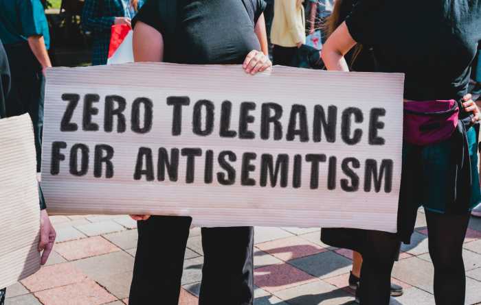 Op-Ed | Defend our democracy by confronting antisemitism 6 The phrase " Zero tolerance for antisemitism " drawn on a carton banner in hand. A girl holds a cardboard with an inscription. Girls on the street. Protest, march. Rally.
