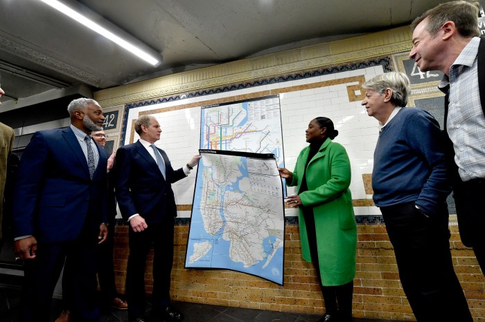 Mapping it out: What do New Yorkers think of the MTA's new subway map? 2 people holding. a map of NYC inside a subway station