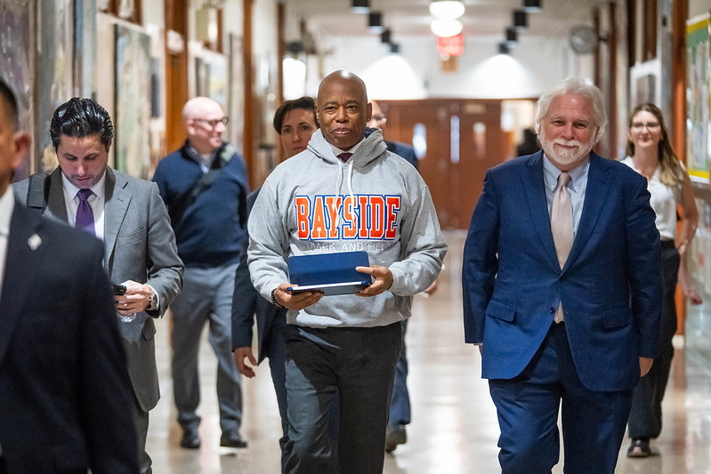 Mayor Adams with officials walking in school hall announcing the NYC budget amid Trump turmoil