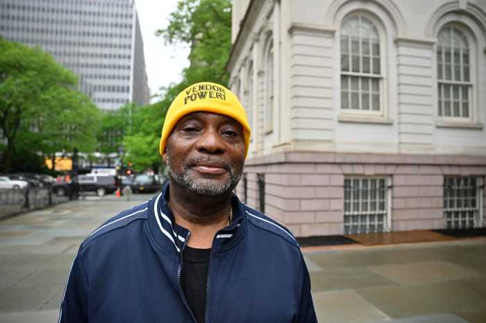 man wearing a yellow hat outside at a street vending rally