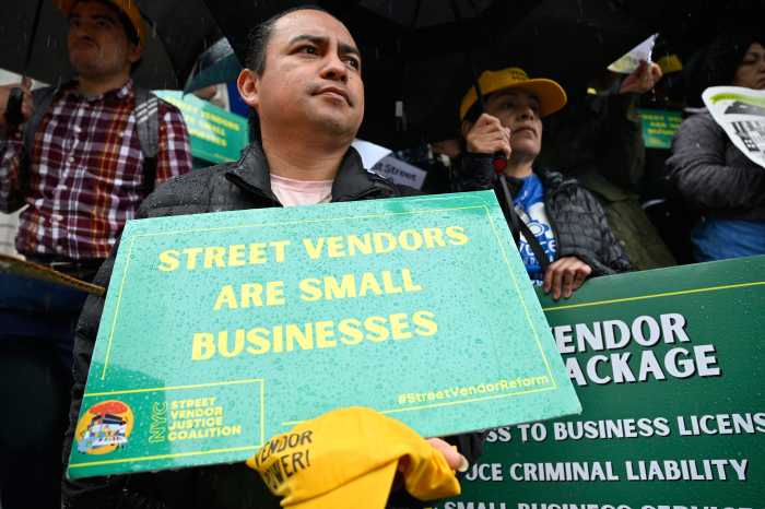 a street vendor holding a green sign in the rain