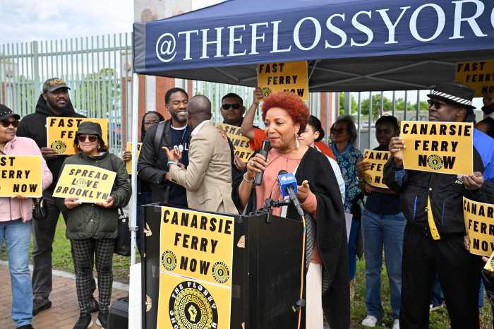 Brooklyn residents rally for a ferry dock in a 'transportation desert' neighborhood 2 peope during the day behind a podium and under a tent