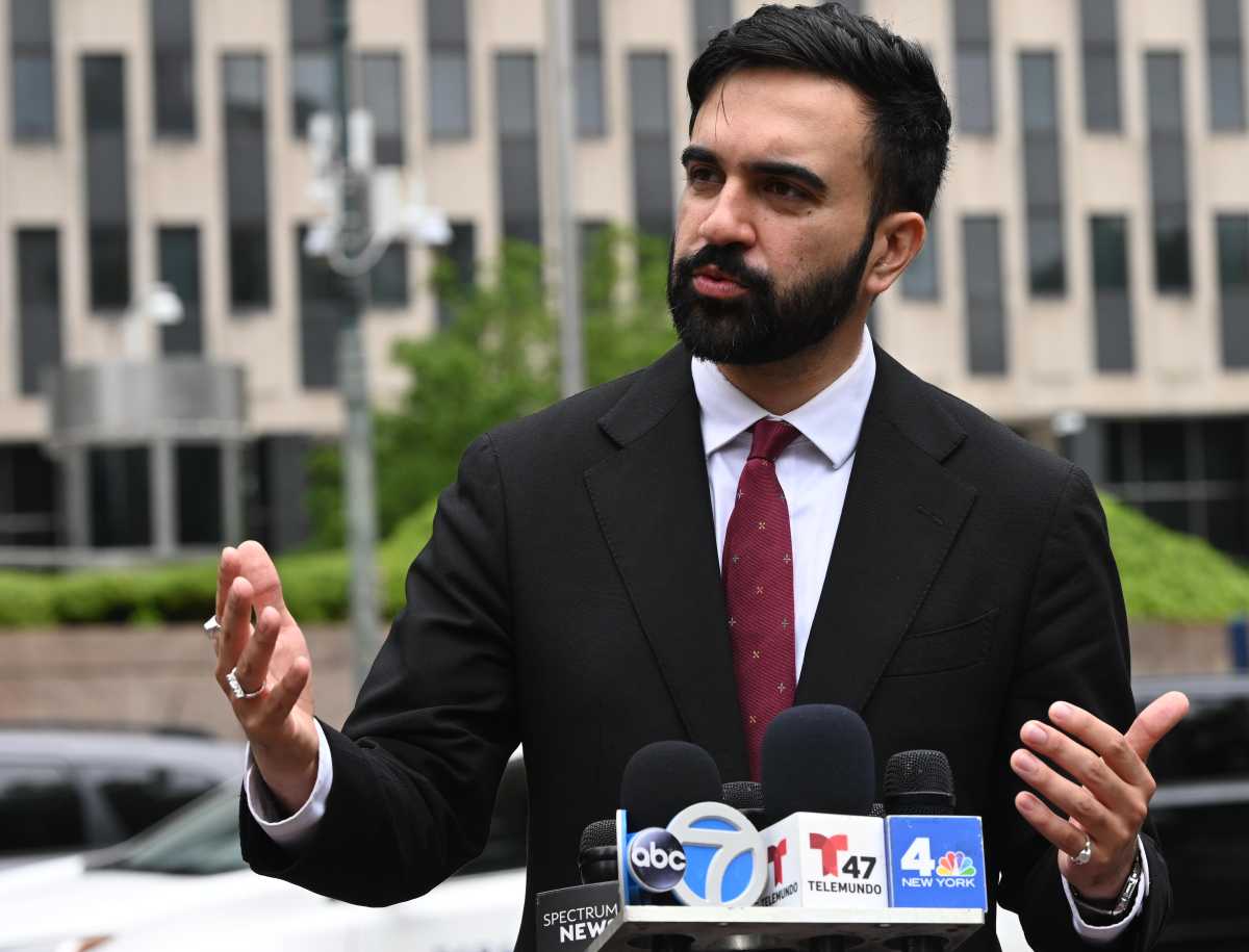 man with beard and suit and tie speaking into tv news microphones Zohran Mamdani