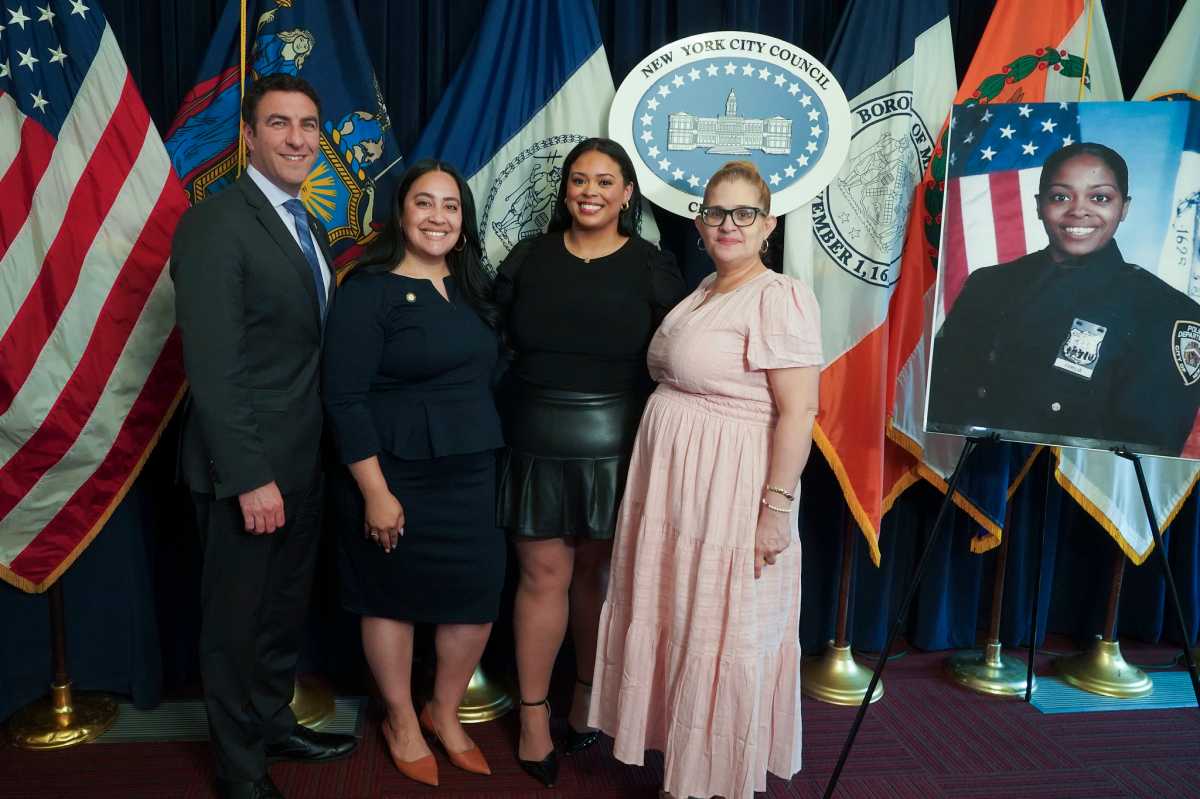four people on a stage next to a photo of an NYPD officer