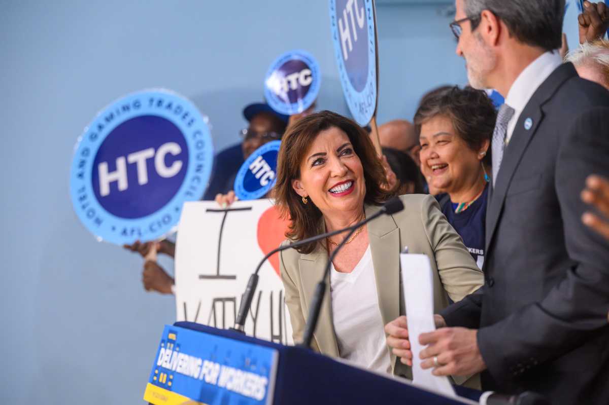 New York State increases unemployment benefits by more than $300 per week, pays off federal unemployment trust loan 1 Woman smiling at podium as people hold union signs