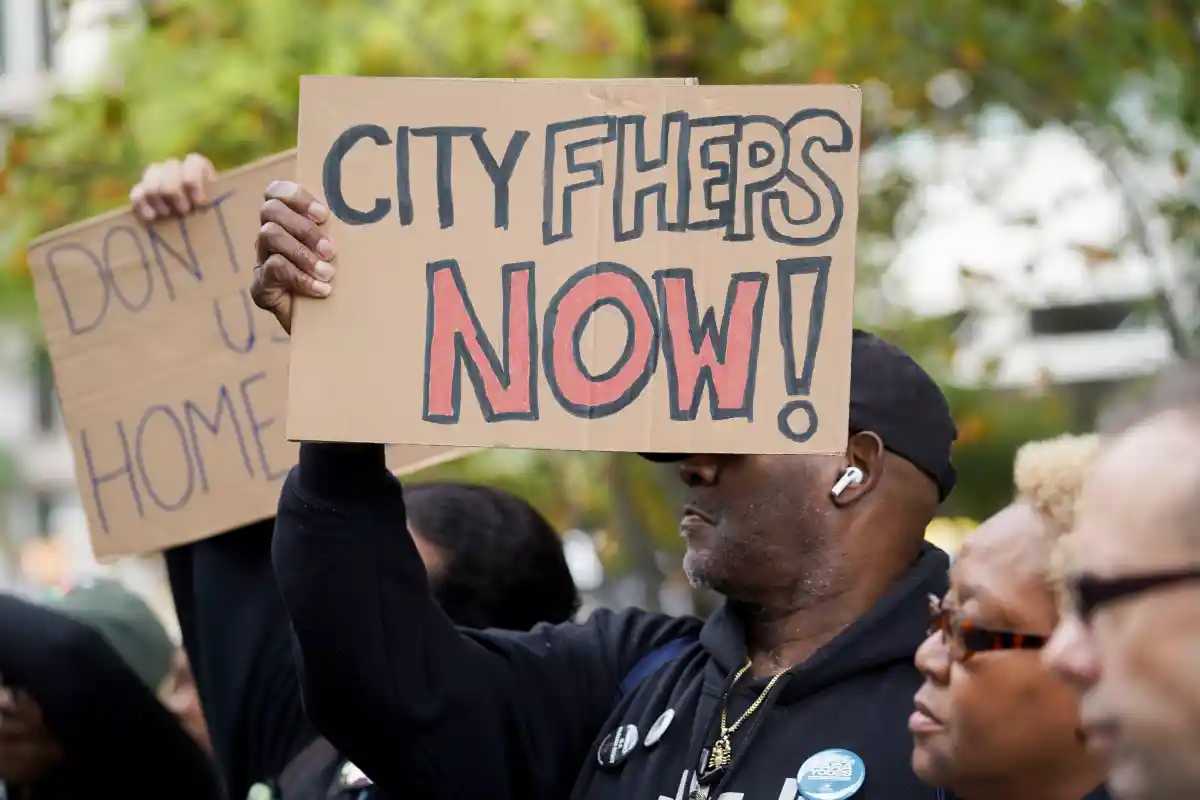A man holds a sign at a rally that reads "CityFHEPS Now!"