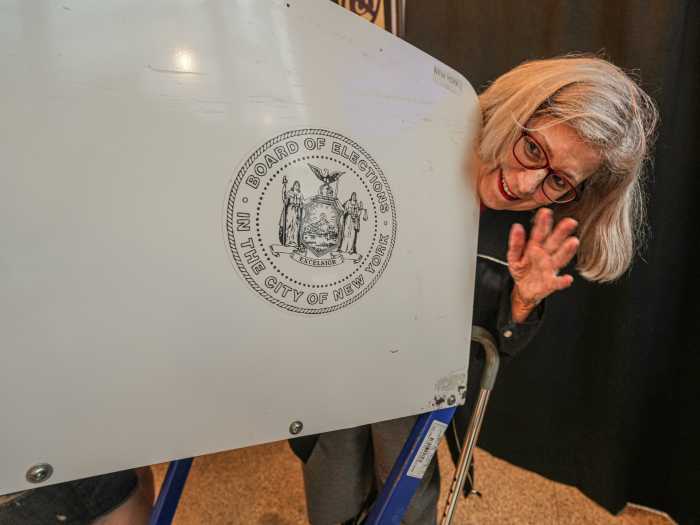 Person peeking over voting booth during early voting in NYC