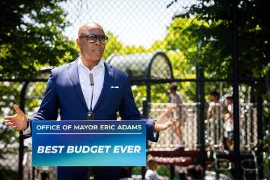 man in sunglasses speaking at podium reading Office of Mayor Eric Adams Best Budget Ever