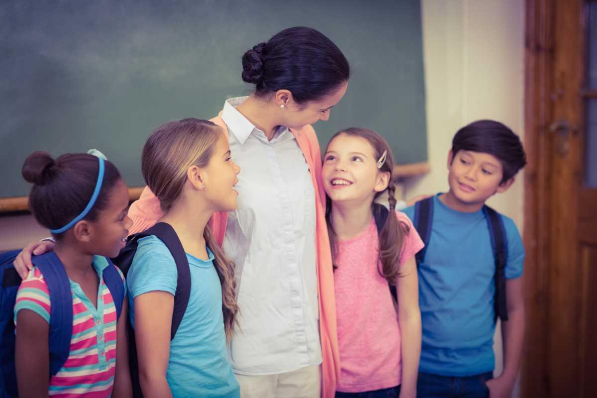 Op-Ed | Delivering universal after-school care for working families 1 Teacher and pupils smiling in classroom at the elementary school