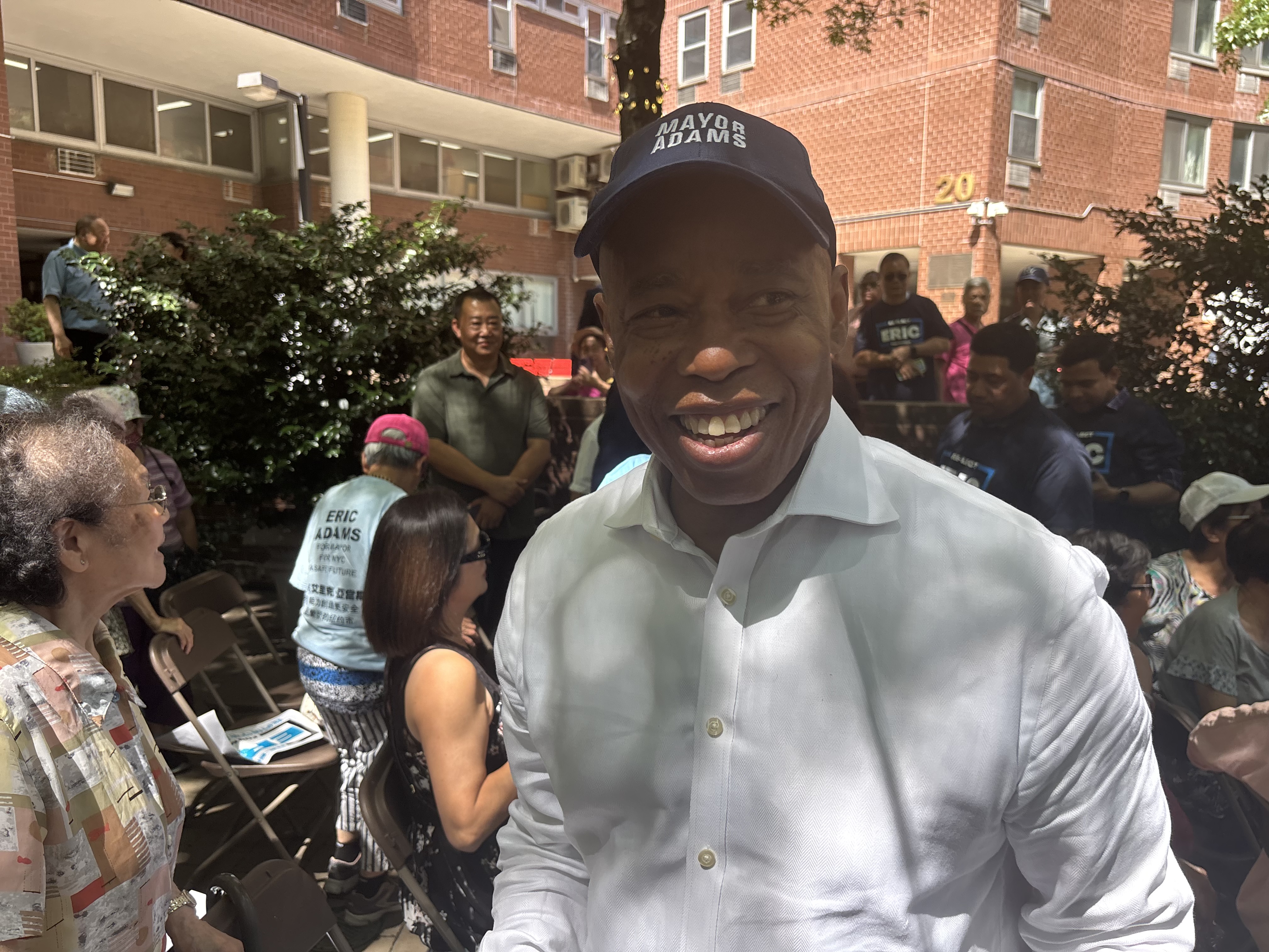 Eric Adams, smiling, wears a hat reading "Mayor Adams."