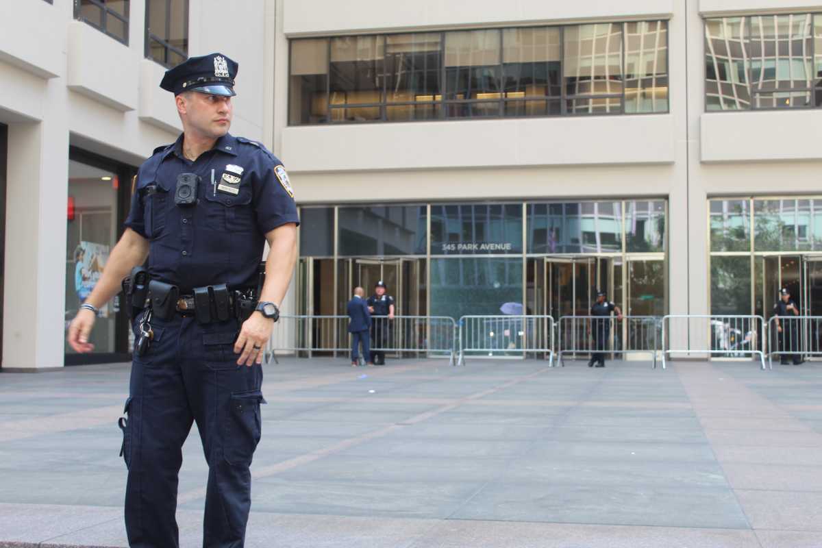 A police officer stands guard at the entrance to 345 Park Ave., the point of entry for the gunman in Monday’s fatal Midtown shooting.
