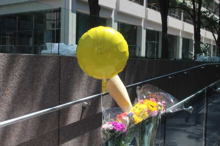 A memorial of flowers and a balloon reading “Love One Another” sits outside 345 Park Ave., honoring the victims of Monday’s deadly shooting.