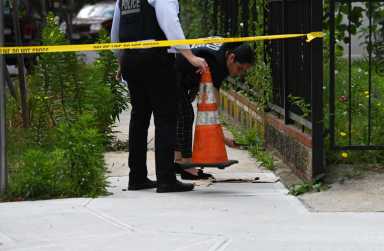 Police officers investigate scene of shooting with cone and yellow tape
