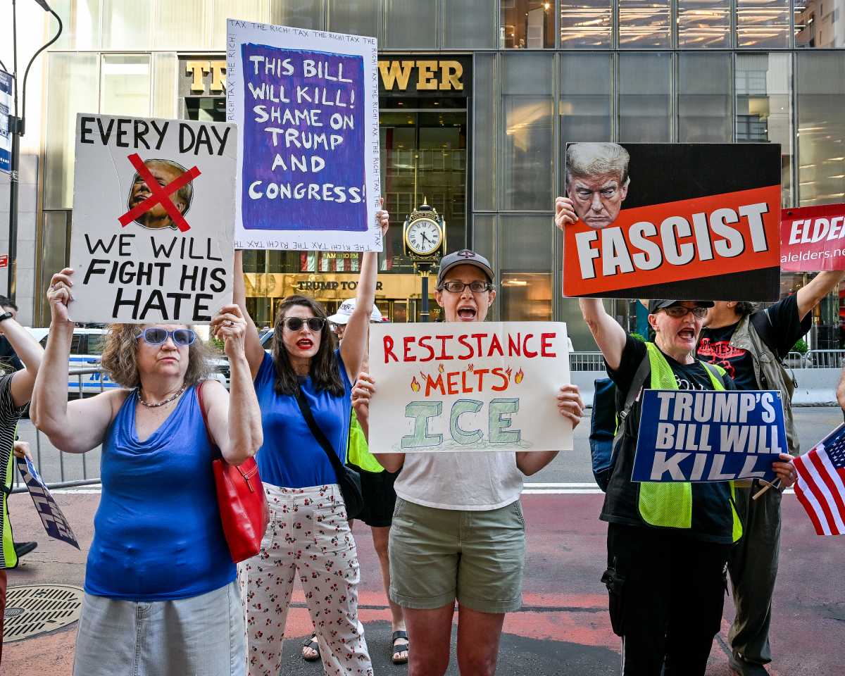People holding signs reading Fascist and condemning Trump for policies