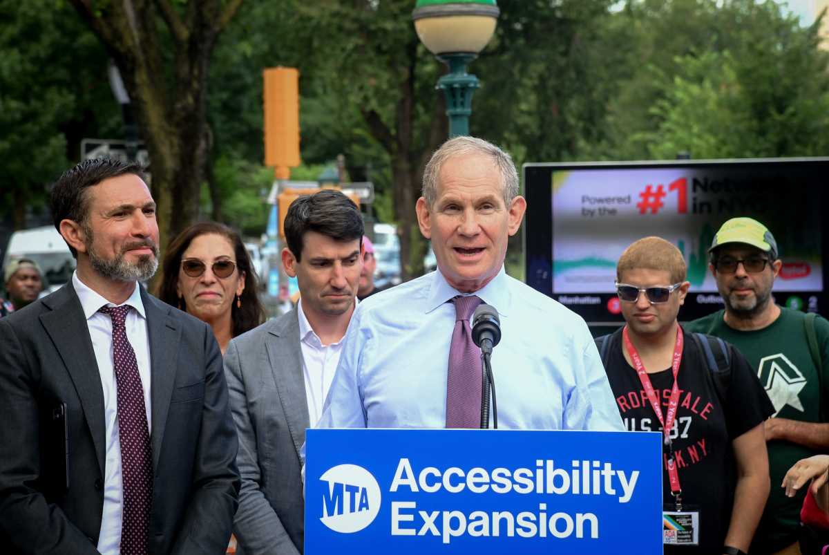 man wearing a purple tie at a podium flanked by a group of people