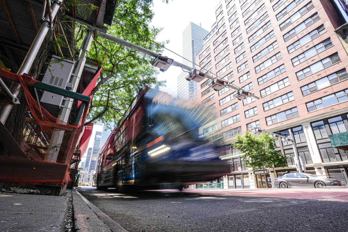 An MTA bus passing under a congestion pricing gantry in Manhattan