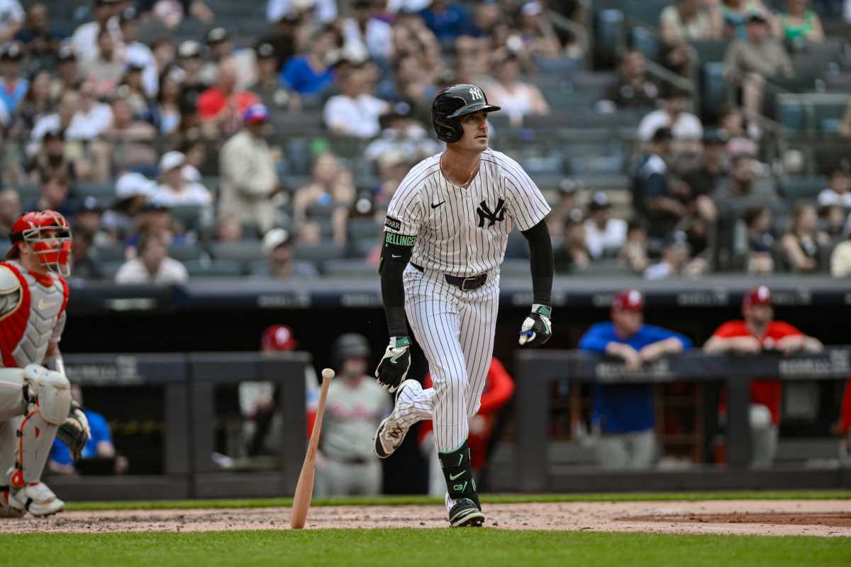 Yankee player in white and pinstripe uniforms runs after getting hit