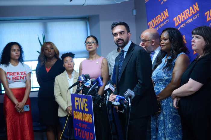 man at podium with suit and beard zohran mamdani speaking about andrew cuomo