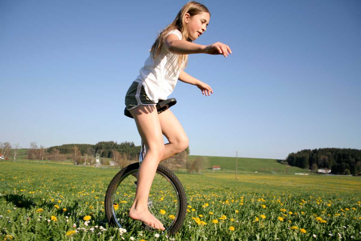 young girl monocycling in field