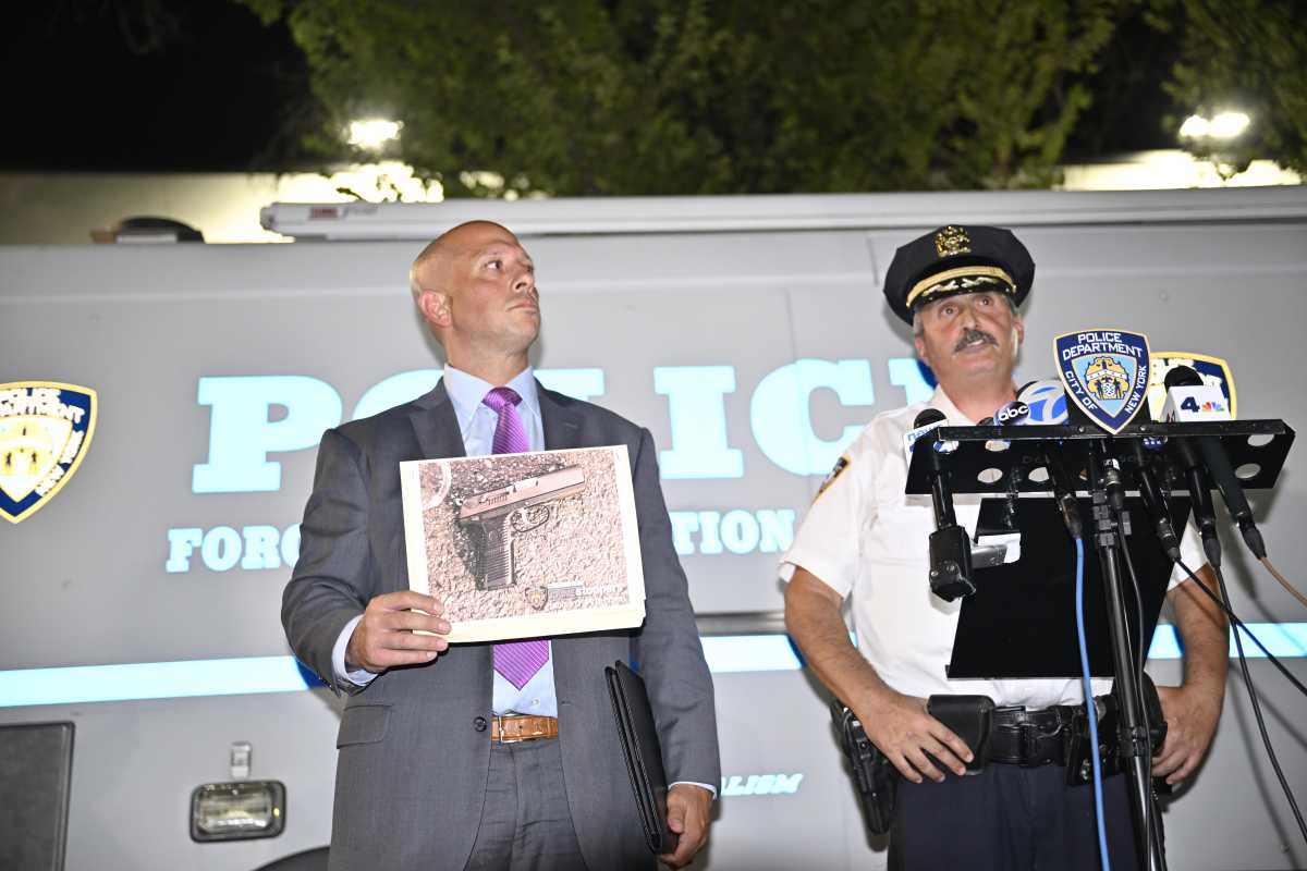 Police officers at scene of Brooklyn shooting holding up photo of confiscated gun