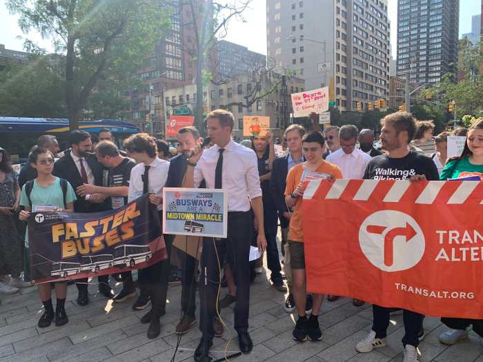 man in a white shirt at a podium surrounded by people