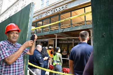 construction crews outside a building with a fallen awning